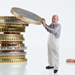 Maler legt Euro-Münze auf Geldstapel